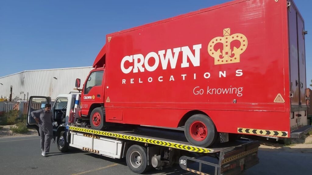 Red box truck carried on a heavy-duty flatbed recovery truck