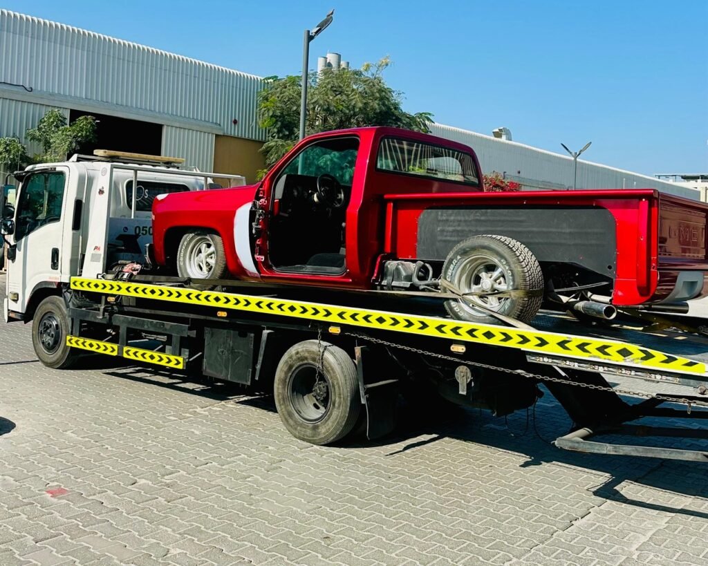Red classic pickup truck being recovered on a flatbed in Dubai