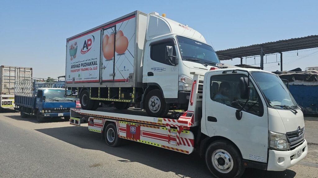 Refrigerated delivery truck loaded onto a flatbed for recovery