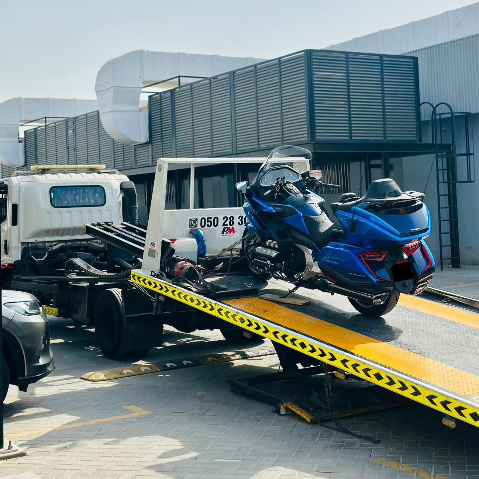 Blue touring motorcycle being loaded onto a tilted flatbed