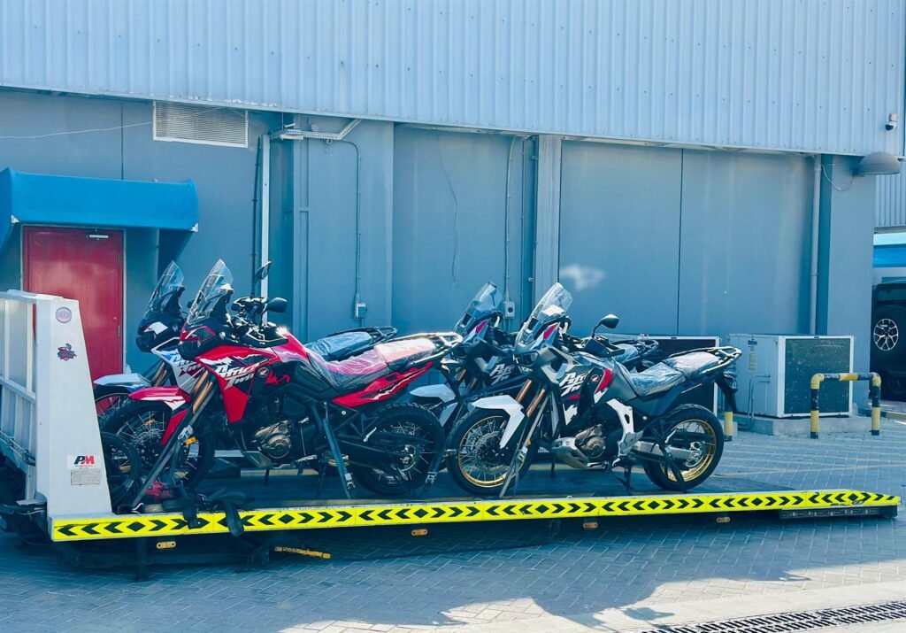 Five adventure motorcycles strapped side by side on one flatbed truck