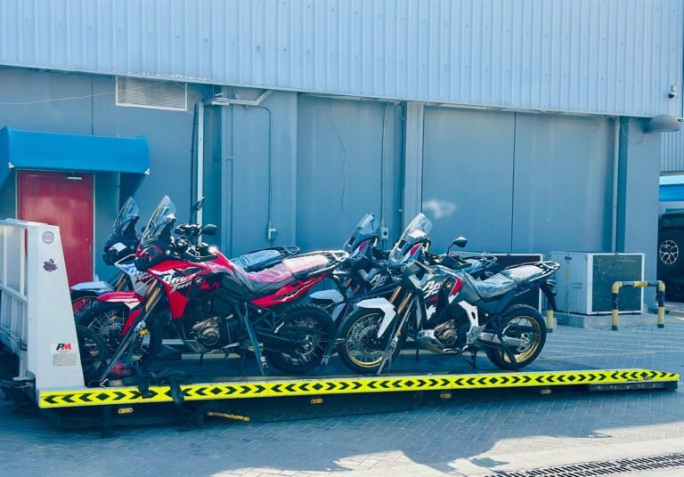 Five adventure motorcycles strapped side by side on one flatbed truck