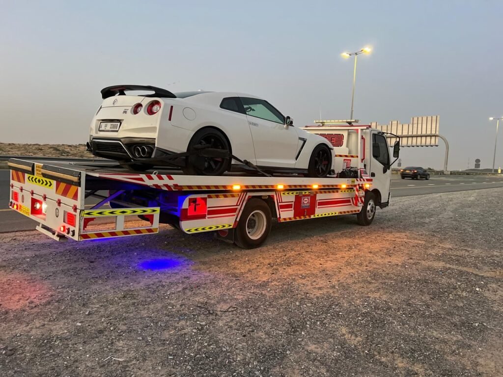 White Nissan GT-R secured on a Sentinal Recovery flatbed truck at dusk in Dubai