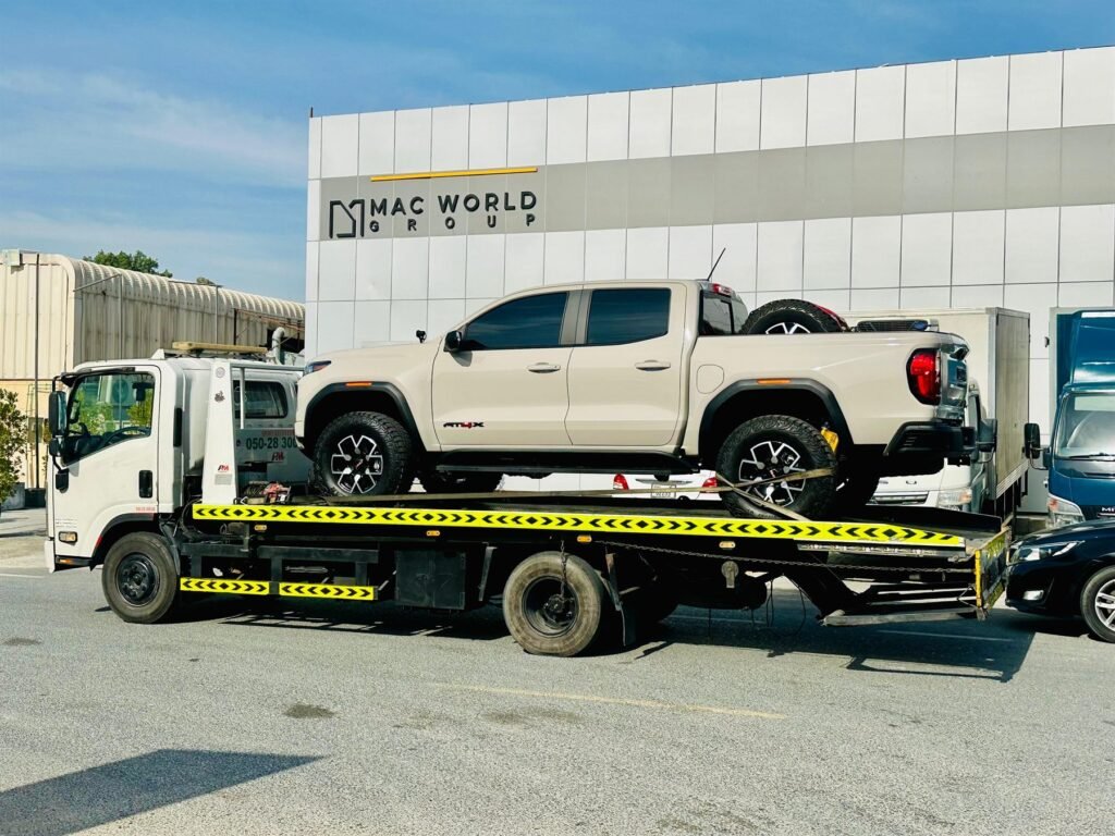 White pickup truck transported on a flatbed recovery truck